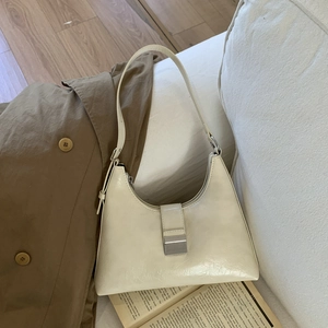 Detail of minimalist cream leather hobo bag with vintage texture and silver buckle clasp