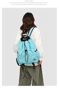 Detail view of a light blue drawstring outdoor backpack with side pockets and a top handle