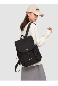 Detail view of black nylon drawstring backpack with top flap and brand logo on a female model