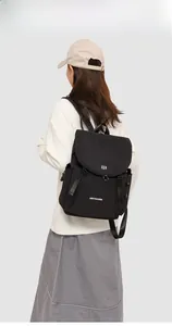 Rear view of a model wearing a black canvas backpack with a drawstring side pocket