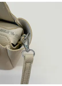 Detail of silver lobster clasp and lychee pattern faux leather strap on beige bucket bag