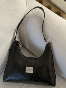 French retro black pleated underarm bag with silver square lock on a white fabric sofa