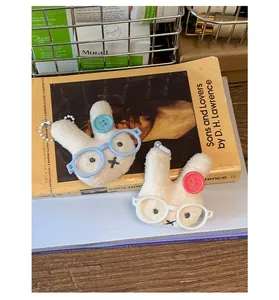 Gros plan de charms lapins en peluche avec lunettes bleues et blanches sur un livre