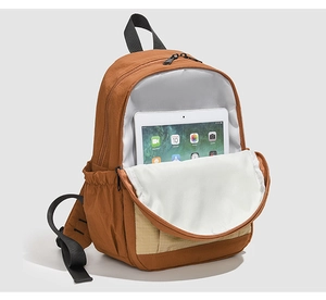 Detail of caramel nylon backpack front pocket showing a tablet for capacity storage