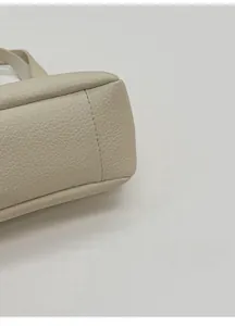 Detailed macro view of cream-colored lychee pattern leather and reinforced bottom stitching