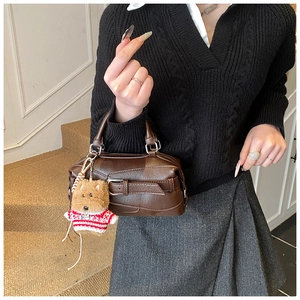 Detailed view of coffee leather handbag featuring belt buckle strap and cute dog pendant
