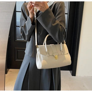 Details der eleganten beigen Ledertasche mit goldenem Drehverschluss und schmalem Schultergurt