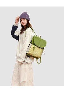 Detail of green and beige drawstring nylon backpack shown on a model with a clean backdrop