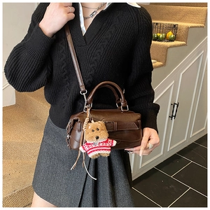 Détail du sac Boston vintage en cuir marron avec un joli pendentif chiot sur l'anse