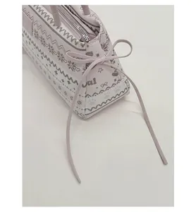 Détail du sac bandoulière rose avec des nœuds décoratifs et des motifs d'étoiles nordiques