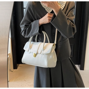 Detailaufnahme der eleganten weißen Lederhandtasche mit goldenem Drehverschluss und Griff