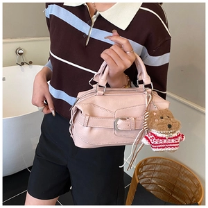 Close-up of pink PU leather handbag with silver buckle and brown teddy bear charm