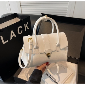 Details aus weißem Litschileder mit goldenem Drehverschluss an der eleganten Handtasche