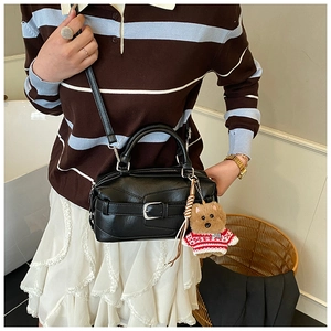 Détail du sac Boston noir tendance avec boucle de ceinture et porte-clé ours mignon