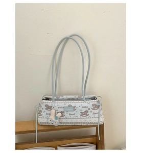 Détail du sac bandoulière en toile bleu clair avec motifs de poulain et breloque lapin