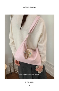 Close-up of soft pink PU leather hobo bag with cute plush pendant and wide shoulder strap