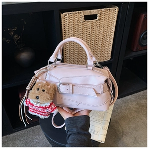 Detail of pink leather handbag with wide buckle strap and cute brown teddy bear charm