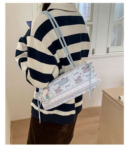 Détail du sac bandoulière cylindrique bleu clair avec porte-clés lapin en peluche