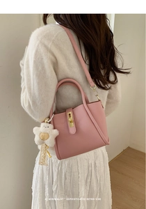 Borsa a secchiello in pelle rosa con chiusura dorata e ciondolo a stella in peluche indossata