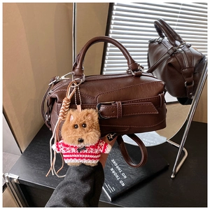 Detail view of a vintage dark brown pillow bag with dog charm and mirror reflection