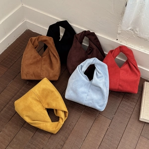 Multi-color suede knot tote bags in yellow, blue, and brown on wooden floor detail