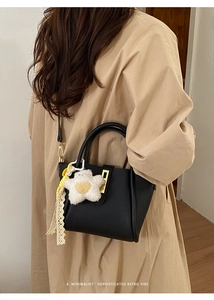 Mini borsa tote nera retrò in pelle a grana con ciondolo a fiore su modella in trench