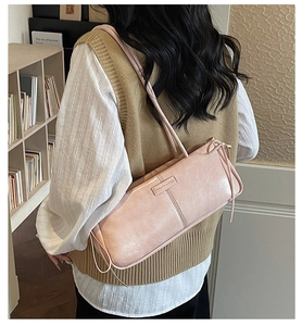 Close-up of pink underarm bag featuring side ribbon bow and fashion brand nameplate