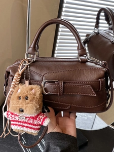 Vintage brown leather Boston bag with dog plush charm and striped sweater accessory