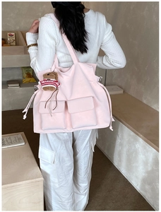 Detail of a large pink tote bag featuring dual front pockets and a cute bear charm