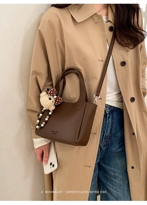 Detail of dark brown leather bucket bag with cute bear charm and polka dot bow accessory