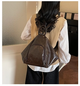 Detail of a vintage dark brown triangular leather backpack with front zipper pocket