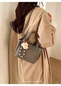 Detail of grey lychee leather bucket bag with cute bear charm and beaded ornament