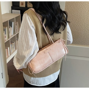 Detailed view of pink leather underarm bag with metal tag and side string ties