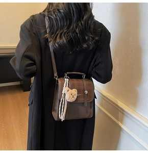 Rear view of model wearing a vintage dark brown plaid flap backpack with a plush bear charm