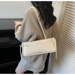 Detail of beige underarm bag with Fashion & Bags logo and side bow decoration