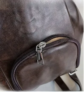 Macro view of a smooth silver zipper and dark brown pleated leather texture on the tote bag