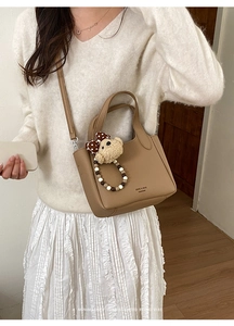 Detail view of khaki leather crossbody bucket bag with cute bear charm and beads