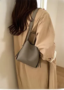 Detail view of dark grey bucket bag with litchi grain leather and wide shoulder strap