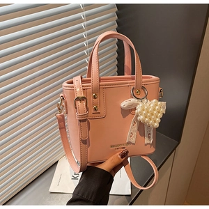 Close-up of pink bucket bag with pearl heart charm and delicate white lace bow