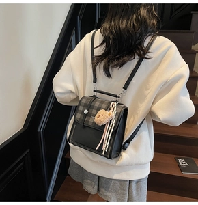 Detail of retro black and gray plaid backpack with cute bear charm and fashion label