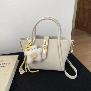 Dettaglio borsa in pelle bianco crema con ciondolo a stella e chiusura dorata