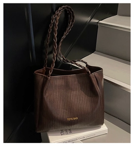Détail d'un sac cabas vintage marron foncé texturé posé sur un livre de décoration