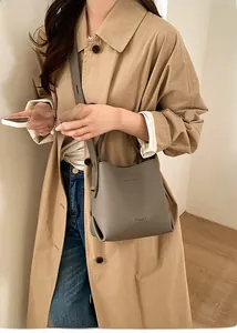 Detail of grey pebbled leather bucket bag with gold-tone branding and slim shoulder strap