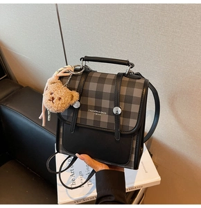 Detail of vintage plaid backpack with metal buckles and a cute plush bear pendant