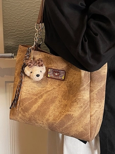 Brown vintage tote bag with bear embossed pattern and plush charm on shoulder