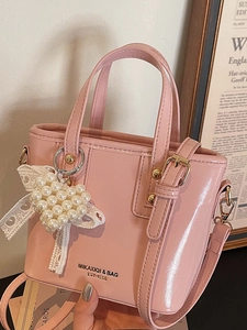 Pink patent leather bucket bag with pearl heart charm and lace bow decoration
