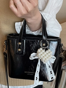 Chic black bucket bag with gold rivets, pearl heart charm and white lace bow