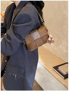 Detail of vintage brown textured crossbody bag with gold chain strap and plush charm