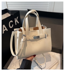 Sac à main beige avec fermoir métallique argenté posé sur un coffret cadeau élégant