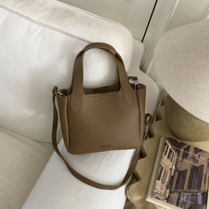 Detailed macro view of the brown lychee-patterned leather mini tote bag on a cozy sofa